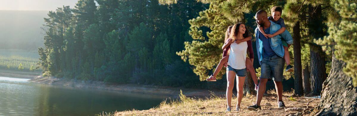 Photo of a happy family walking along the shoreline in a forest campground