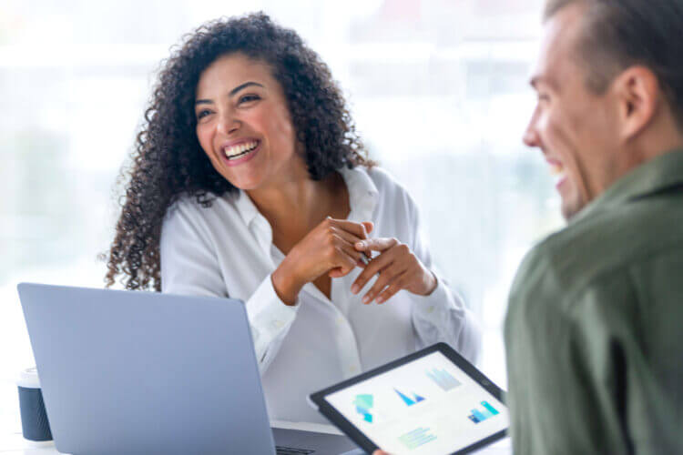 Curly-haired lady and man meeting around a laptop and tablet