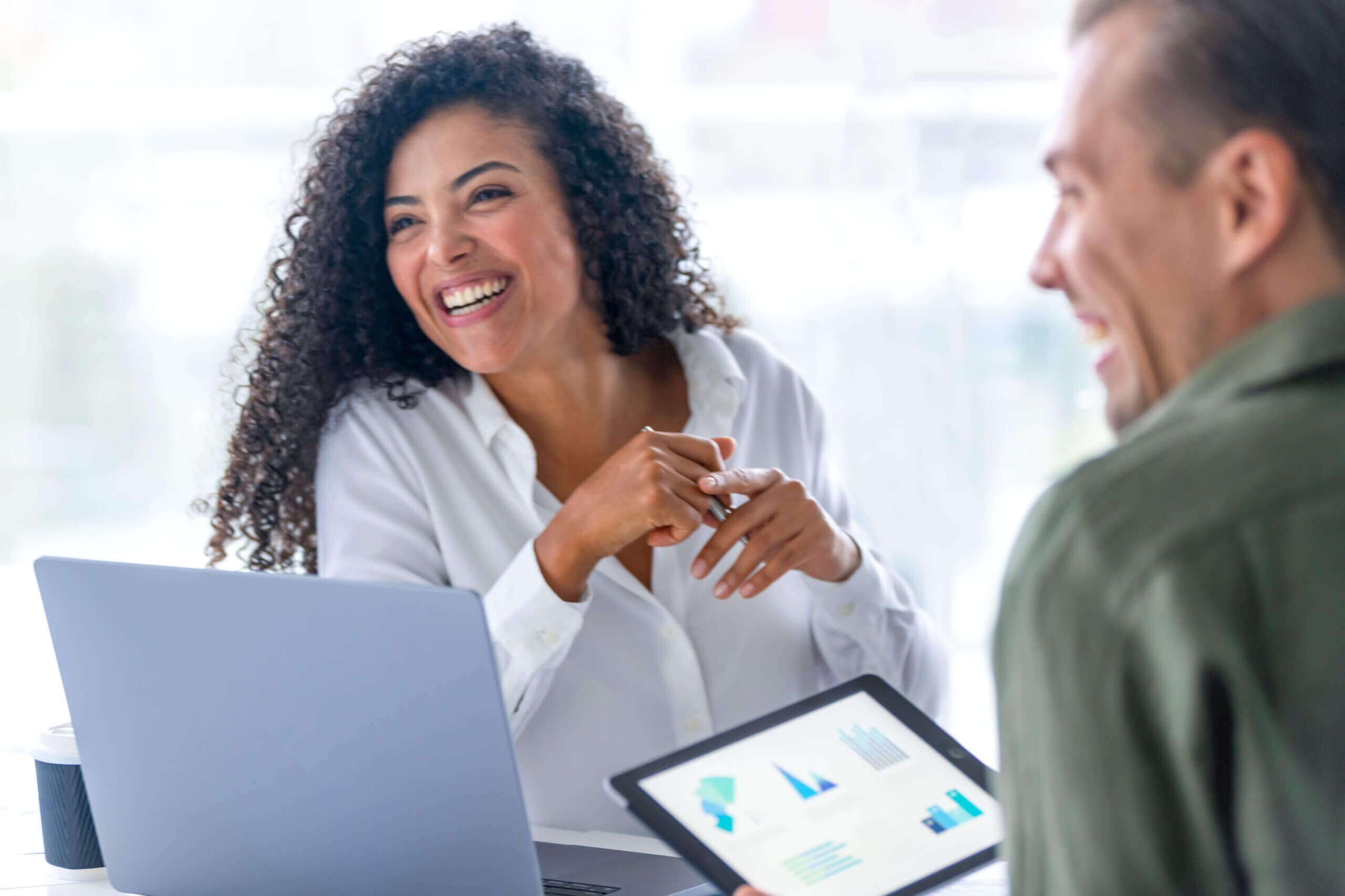 Curly-haired lady and man meeting around a laptop and tablet