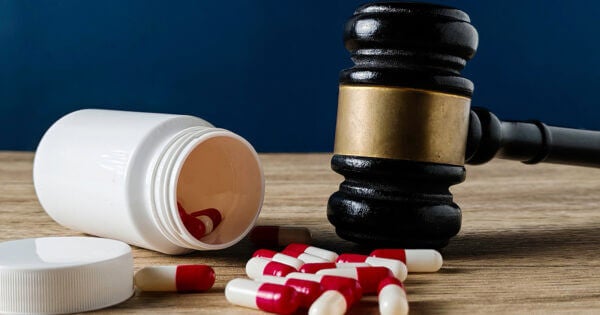 spilled pills on a desk by a gavel