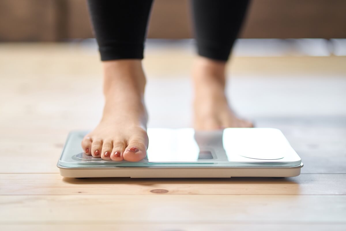Close-up of a woman's feet as she is stepping on a home digital scale to check her weight.