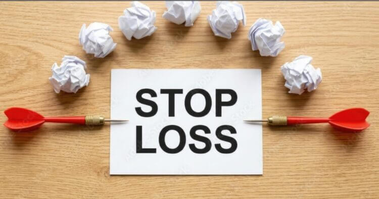 two red dart aiming at paper with words Stop Loss. Wads of white paper surrounding the sign.